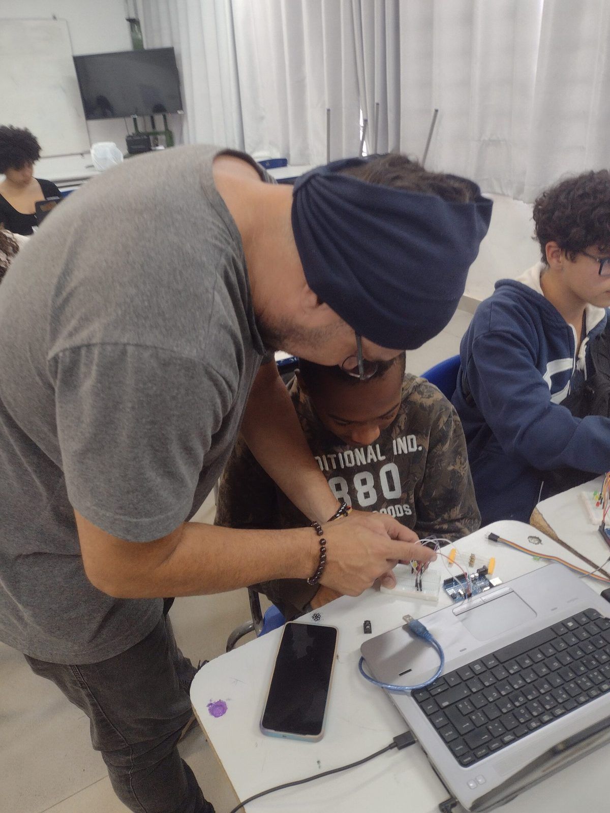 Jovens em oficina maker do Hackerclubes montando eletrônica em grupo
