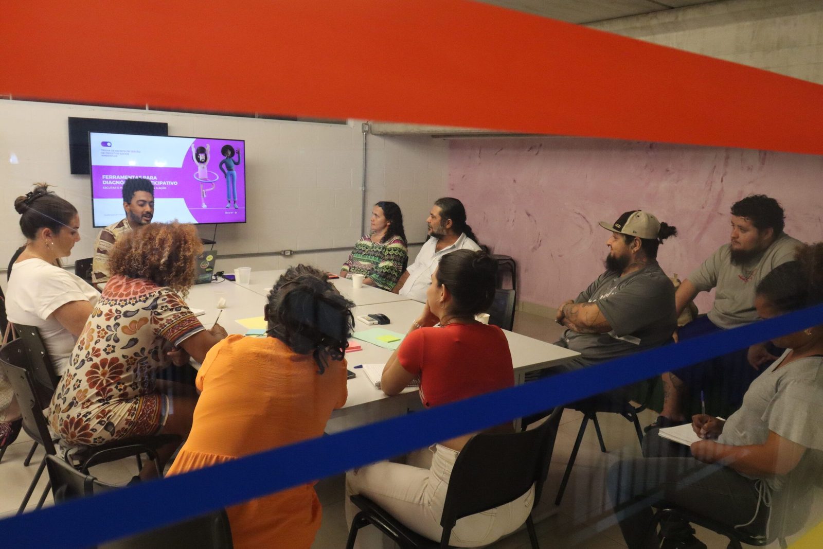 Grupo de participantes reunido em uma sala acompanha apresentação sobre diagnóstico participativo durante atividade formativa.